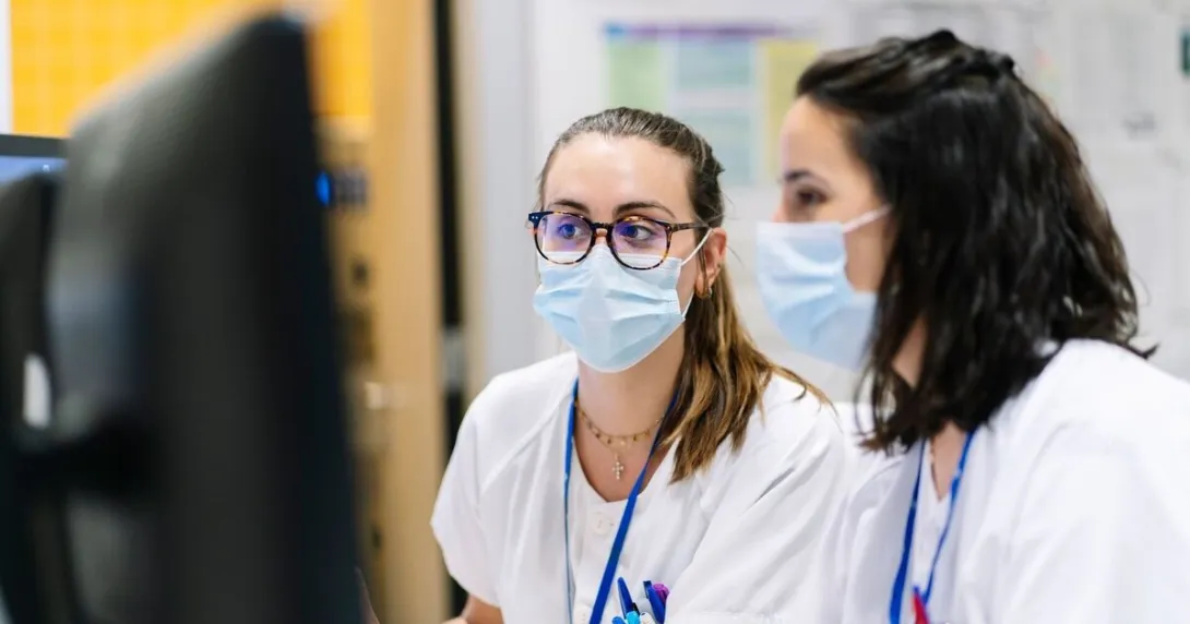 Two hospital staff facing a desktop computer